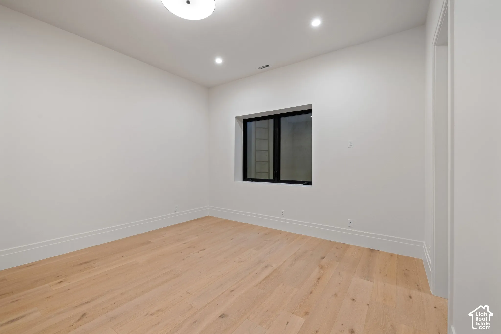 Room featuring wood-finish flooring, recessed lighting, and a window with a black frame