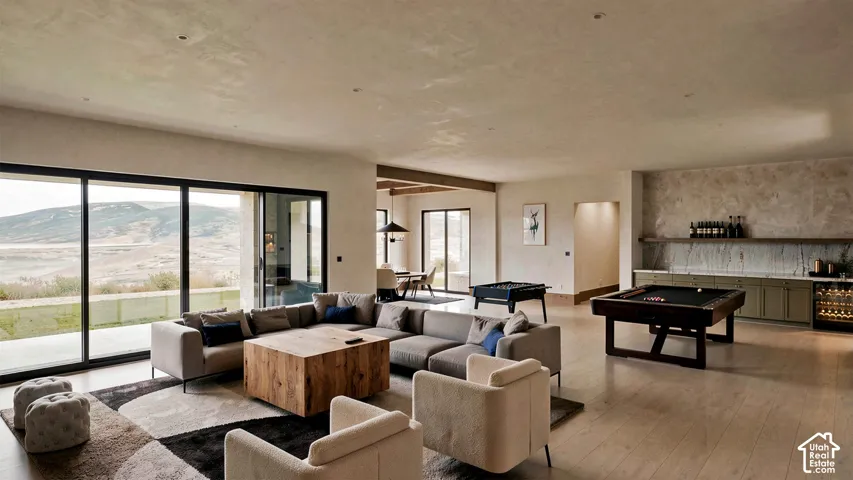 Expansive open-concept living area featuring wood-finish flooring, floor-to-ceiling sliding glass doors, textured wall finishes, and a built-in wet bar with stone backsplash and custom cabinetry