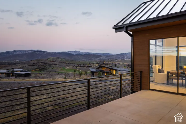 Covered concrete terrace featuring a metal cable railing, horizontal wood siding, metal roof, and floor-to-ceiling glass panel windows