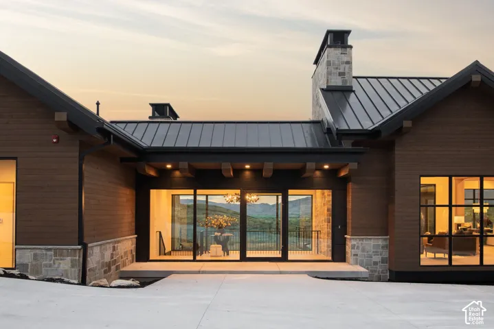 Exterior featuring horizontal wood siding, stone veneer base, metal roof, and an expansive window wall with mountain backdrop