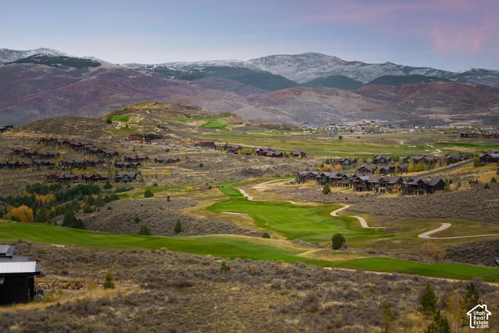 Aerial perspective of mountainous terrain featuring expansive golf course fairways, native high-desert vegetation, and snow-capped peaks