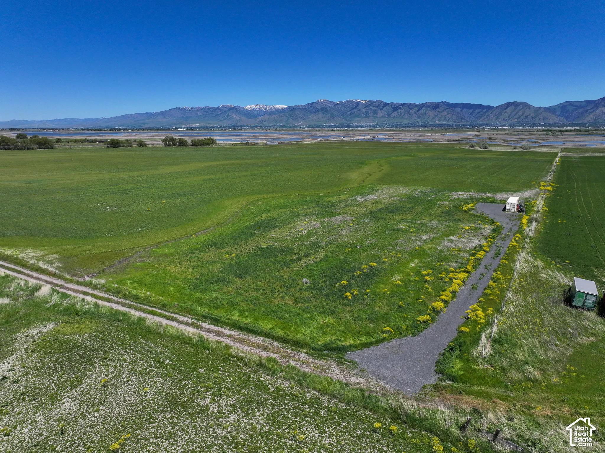 Expansive parcel of land featuring open acreage, a gravel access path, and a mountain range backdrop