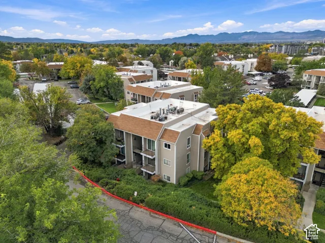 Multi-story residential structure featuring beige siding, brown shingle mansard roofing, tiered balconies, and established landscaping