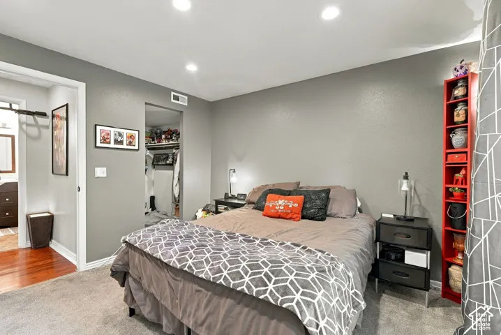 Neutral-toned walls paired with recessed ceiling lighting, carpeted flooring, and a walk-in closet