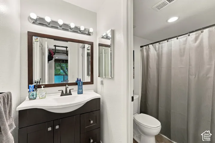 Bathroom featuring an espresso-finish vanity with a curved integrated sink, dark-tone widespread faucet, multi-bulb vanity light, and a shower-tub combination