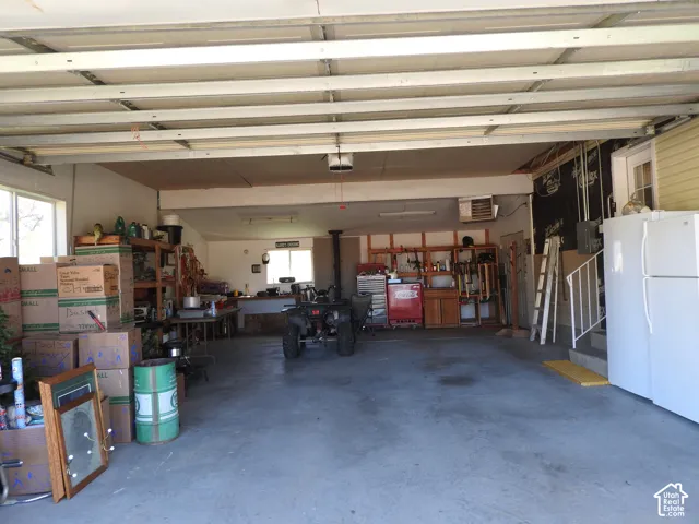 Multi-car garage featuring a concrete floor, built-in wooden shelving, and a metal-framed service door