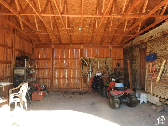 Outbuilding featuring exposed wooden roof trusses, vertical wood-plank wall construction, and a dirt floor