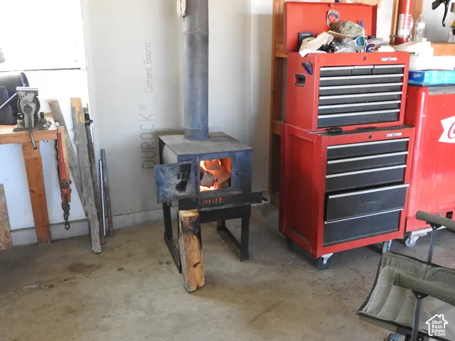 Freestanding metal wood-burning stove with vertical stovepipe and cement board wall backing