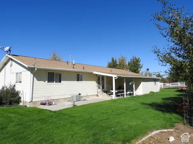 Single-story residence featuring light-colored horizontal siding, a composition shingle roof, a covered concrete patio, and a manicured lawn