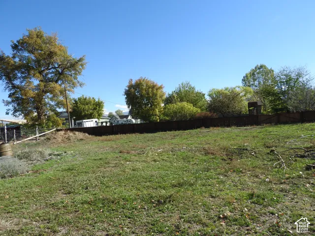 Expansive lot featuring mature trees, wood-slat perimeter fencing, and open ground