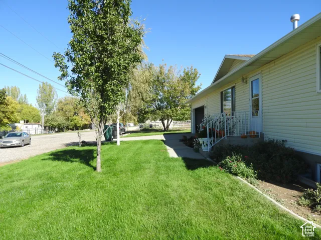 Exterior featuring horizontal siding, a concrete entryway, metal handrails, and a mature tree-lined lawn