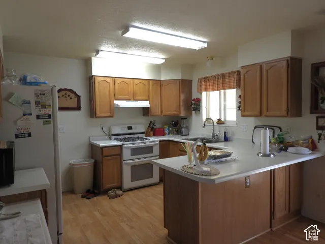 Kitchen featuring wood cabinetry, white solid-surface countertops, wood-finish flooring, and recessed overhead lighting