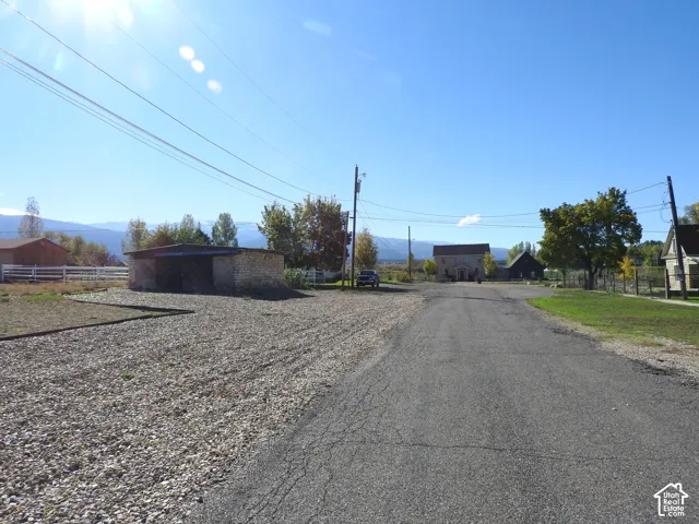 Expansive lot featuring gravel-surfaced grounds, stone-exterior outbuildings, white fencing, and mountain scenery