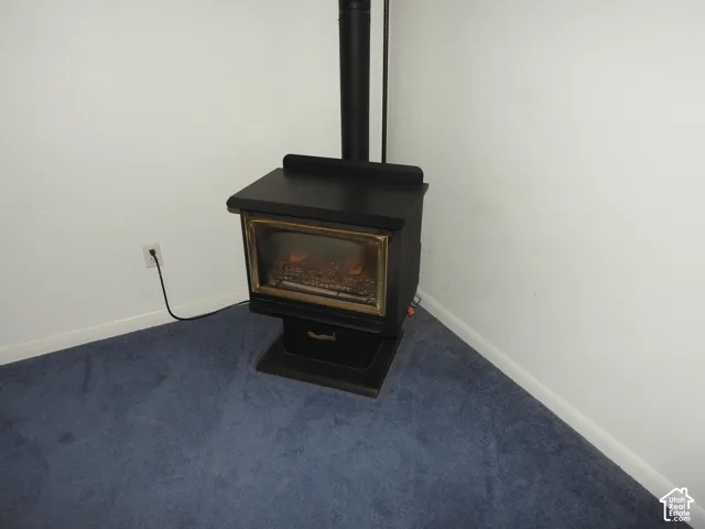 Black metal freestanding wood-burning stove featuring a glass-panel door and vertical chimney pipe