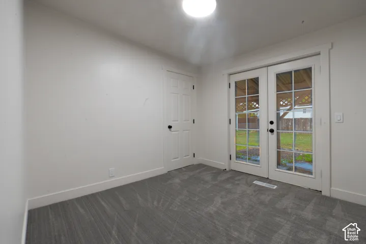Neutral interior featuring gray wall-to-wall carpeting, white walls, a single-panel interior door, and French doors with glass panes