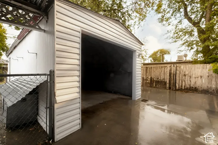 Detached garage featuring horizontal siding, a concrete parking pad, and perimeter wood fencing