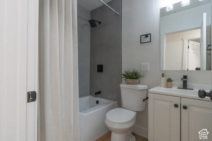 Bathroom featuring a vanity with a white cabinet and square sink, matte black faucet, rectangular frameless mirror, and a tub enclosure with gray large-format tile surround and matte black fixtures