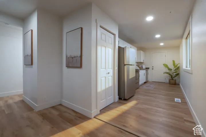 Kitchen featuring wood-finish flooring, recessed lighting, white cabinetry, and stainless steel appliances