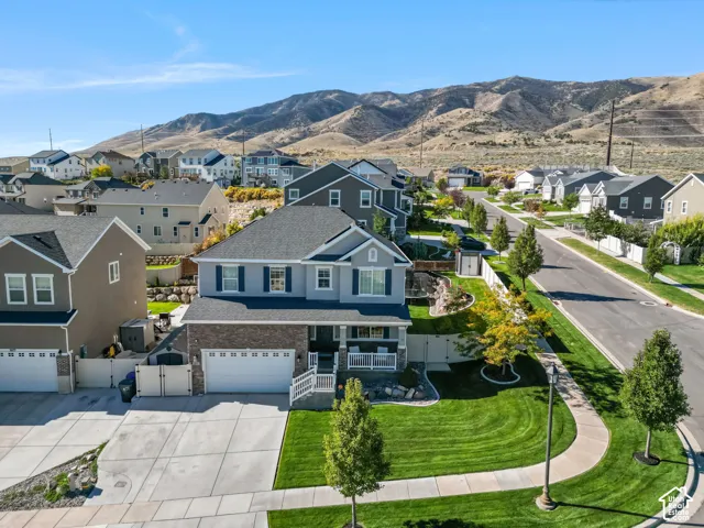 Two-story residence featuring a stone and siding exterior, two-car garage, front porch, and manicured lawn, framed by a prominent mountain backdrop