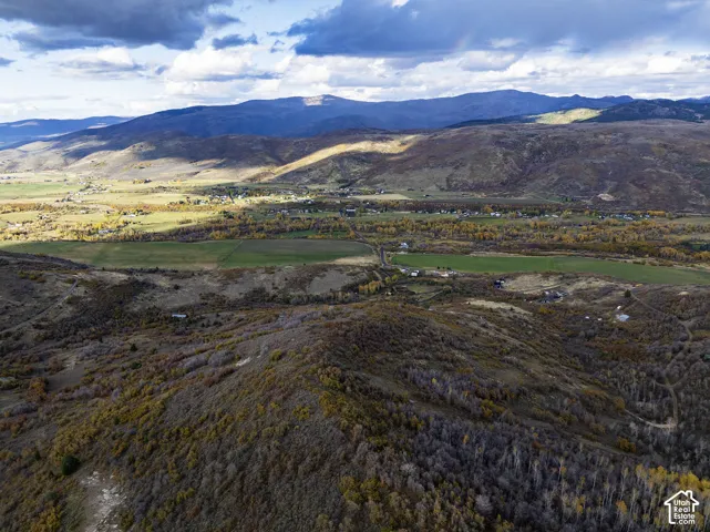Aerial perspective featuring expansive mountain ranges, rolling foothills, and open valley terrain