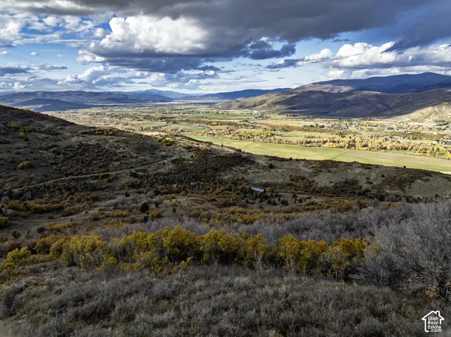Expansive mountain topography featuring rolling foothills, a vast valley floor, and mature vegetation