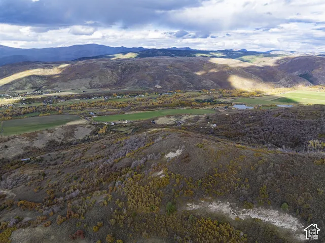 Aerial perspective showcasing expansive mountain topography, rolling hills, native vegetation, and surrounding valley acreage