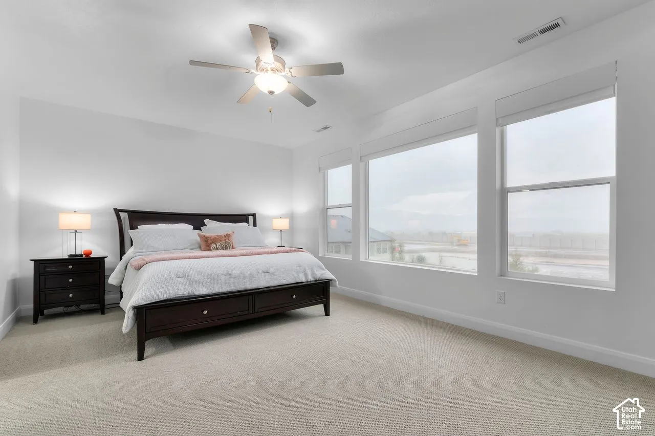 High-ceilinged room featuring carpeted flooring, a central ceiling fan with an integrated light fixture, and expansive windows