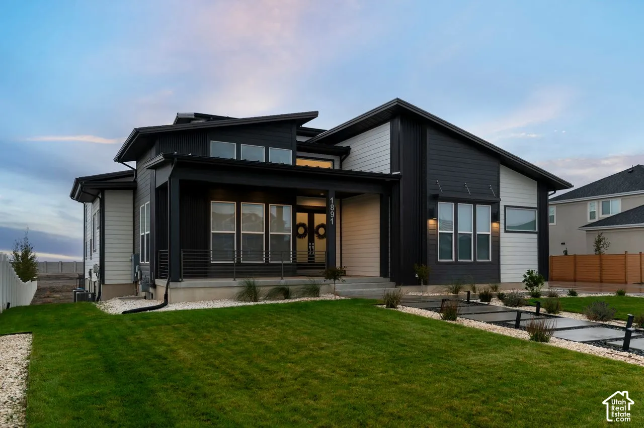 Contemporary exterior featuring high-contrast siding, a covered front porch with horizontal metal railing, multiple shed rooflines, and a linear paver walkway
