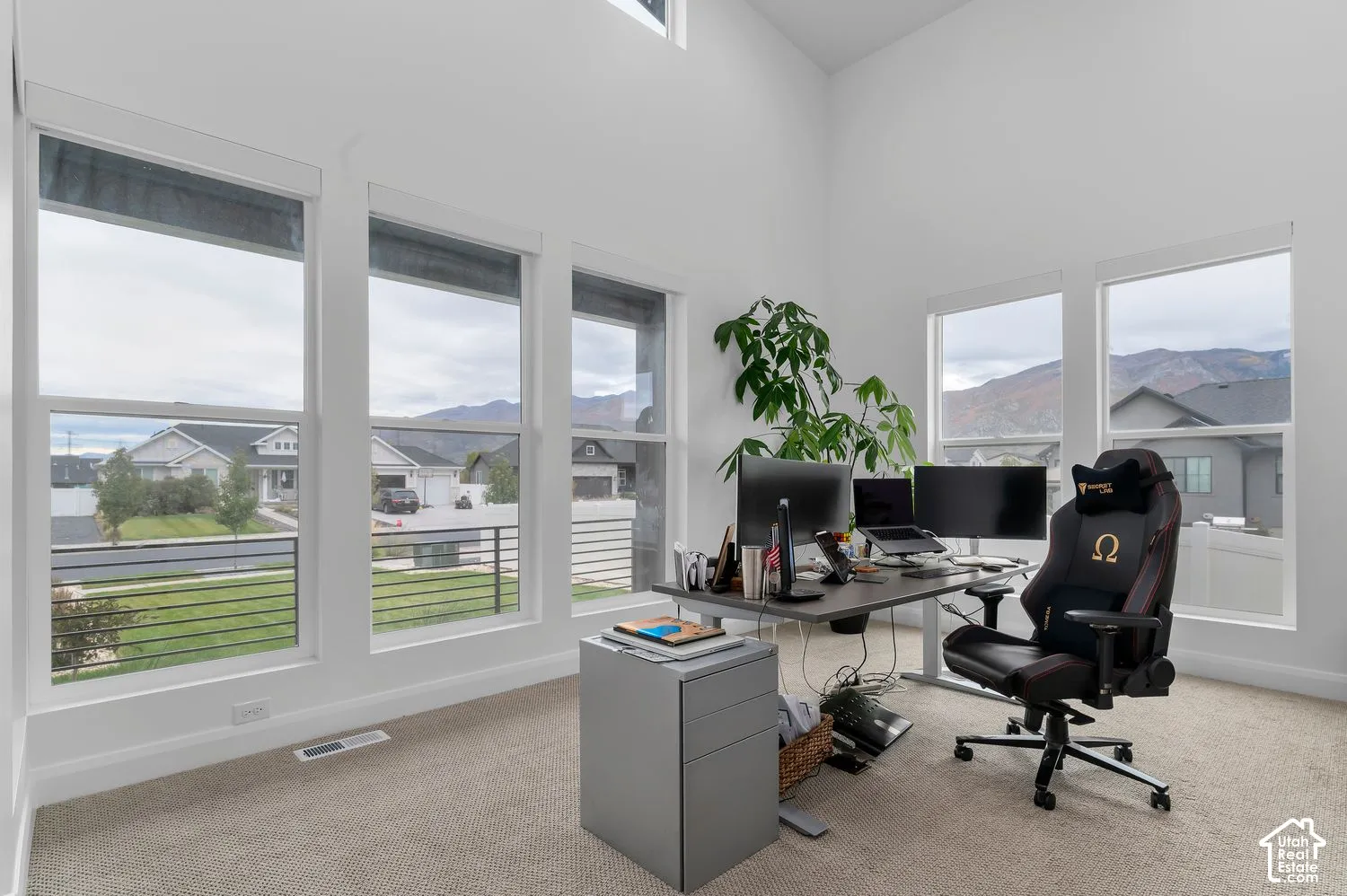 Vaulted ceilings, five large windows providing natural light, neutral carpeting, and prominent mountain scenery