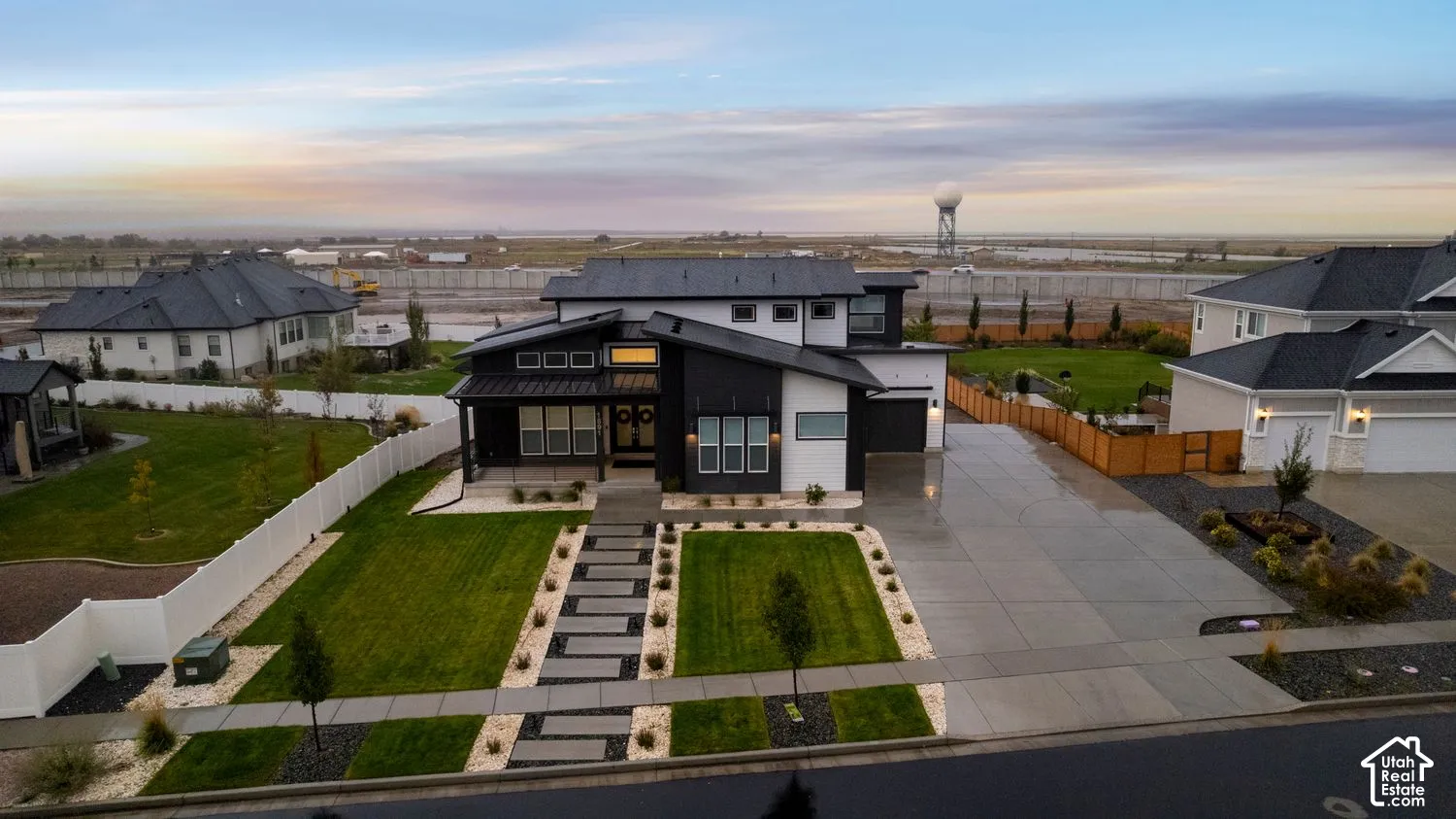 Modern architectural exterior featuring high-contrast two-tone siding, a multi-gabled roofline with metal roofing accents, a stone-paved walkway, and a concrete driveway