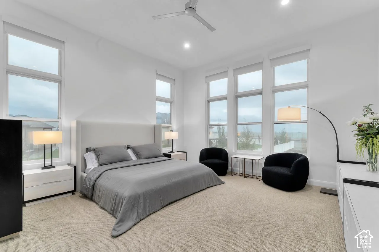 High-ceilinged room featuring large, multi-pane windows, neutral carpet flooring, recessed lighting, and a modern ceiling fan