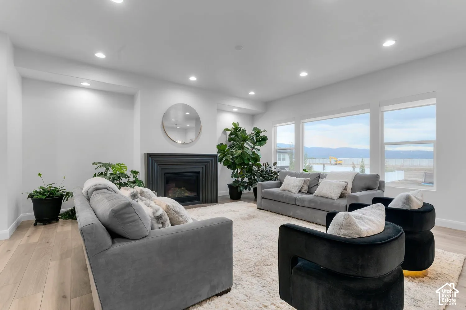 Living area featuring wood-finish flooring, recessed lighting, expansive windows, and a built-in fireplace with a tiered surround