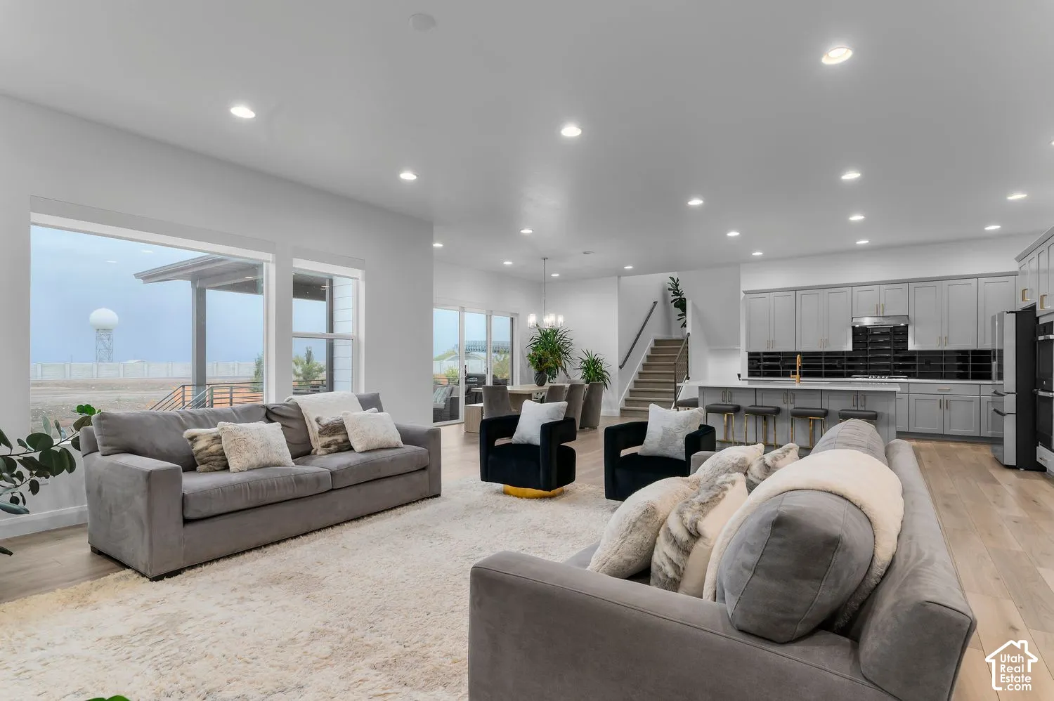 Open floor plan featuring wood-finish flooring, recessed lighting, expansive windows, light-toned cabinetry, and a large central island
