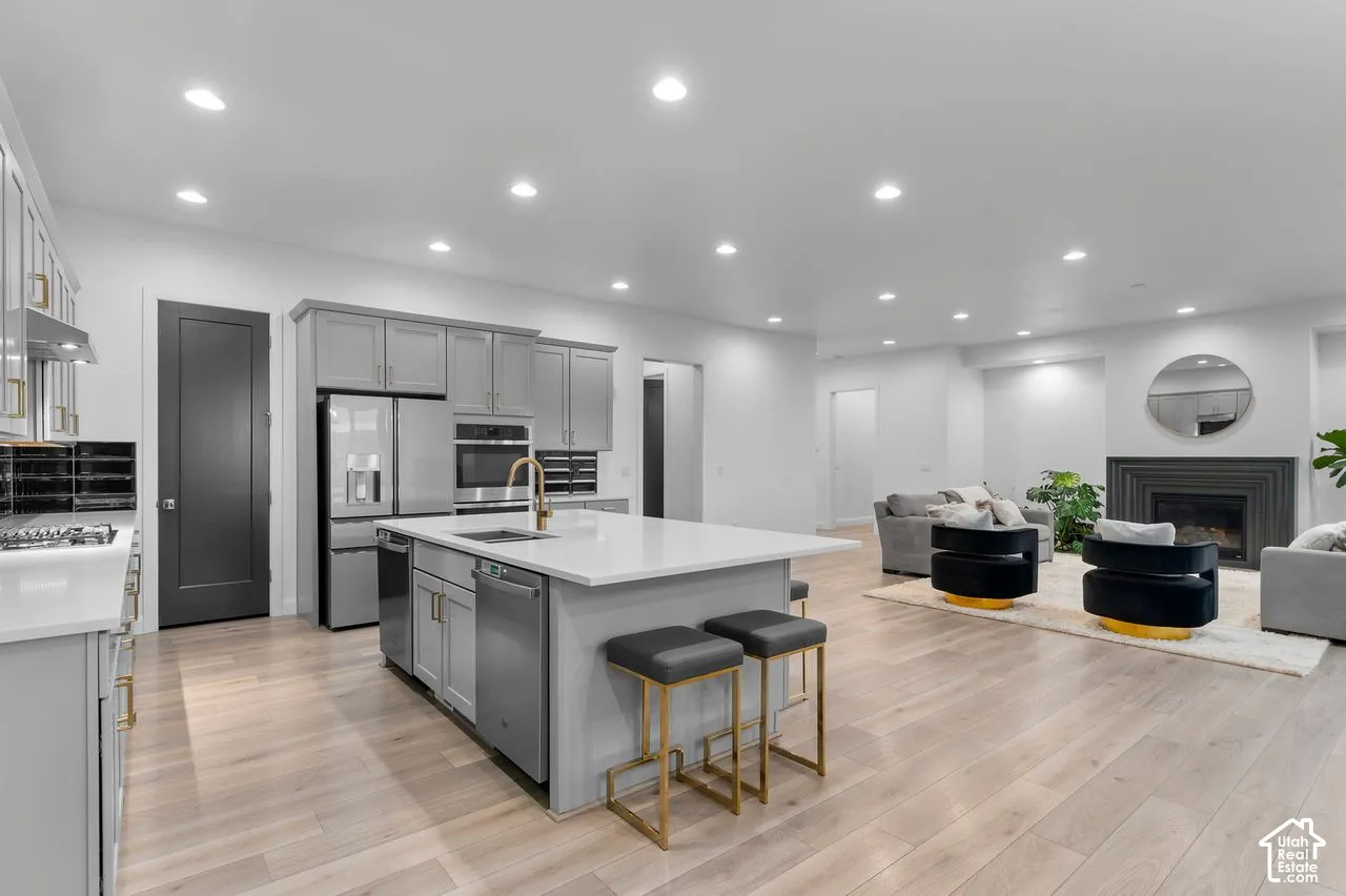 Kitchen featuring an island with quartz countertop, grey cabinetry, stainless steel appliances, wood-finish flooring, and recessed lighting