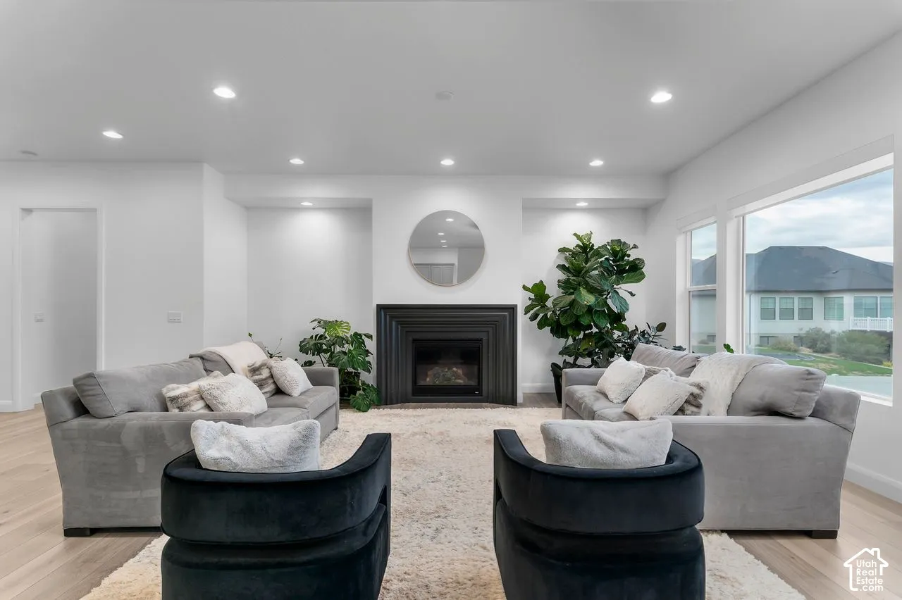 Living area featuring wood-finish flooring, recessed lighting, and a fireplace with a black tiered surround
