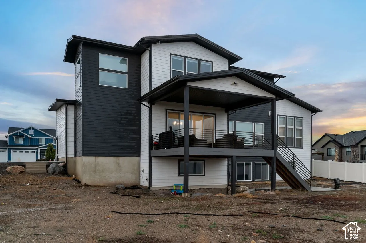 Two-story exterior with horizontal siding, a covered upper-level deck, metal railings, and an attached staircase