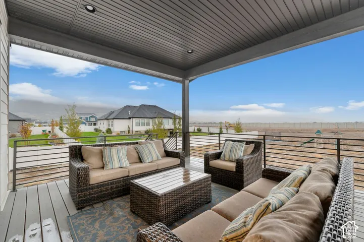 Covered patio featuring composite decking, horizontal metal railings, and a tongue-and-groove ceiling with recessed lighting