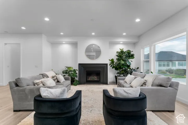 Living area featuring wood-finish flooring, recessed lighting, and a fireplace with a black tiered surround