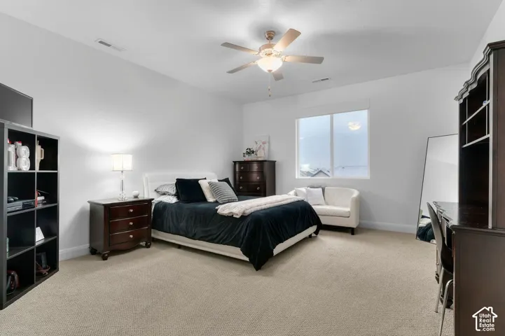Spacious room featuring neutral carpeting, a central ceiling fan with integrated light fixture, and a large window