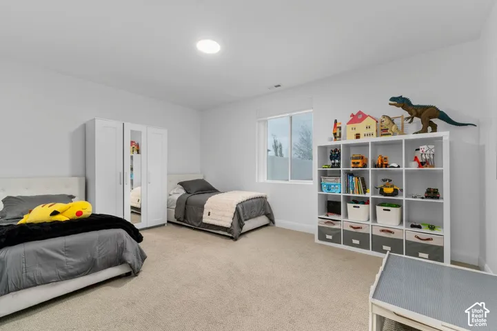 Neutral-toned interior space featuring neutral wall-to-wall carpeting, a large sliding-sash window, and a recessed ceiling light fixture