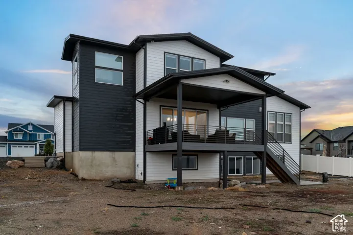 Two-story exterior with horizontal siding, a covered upper-level deck, metal railings, and an attached staircase