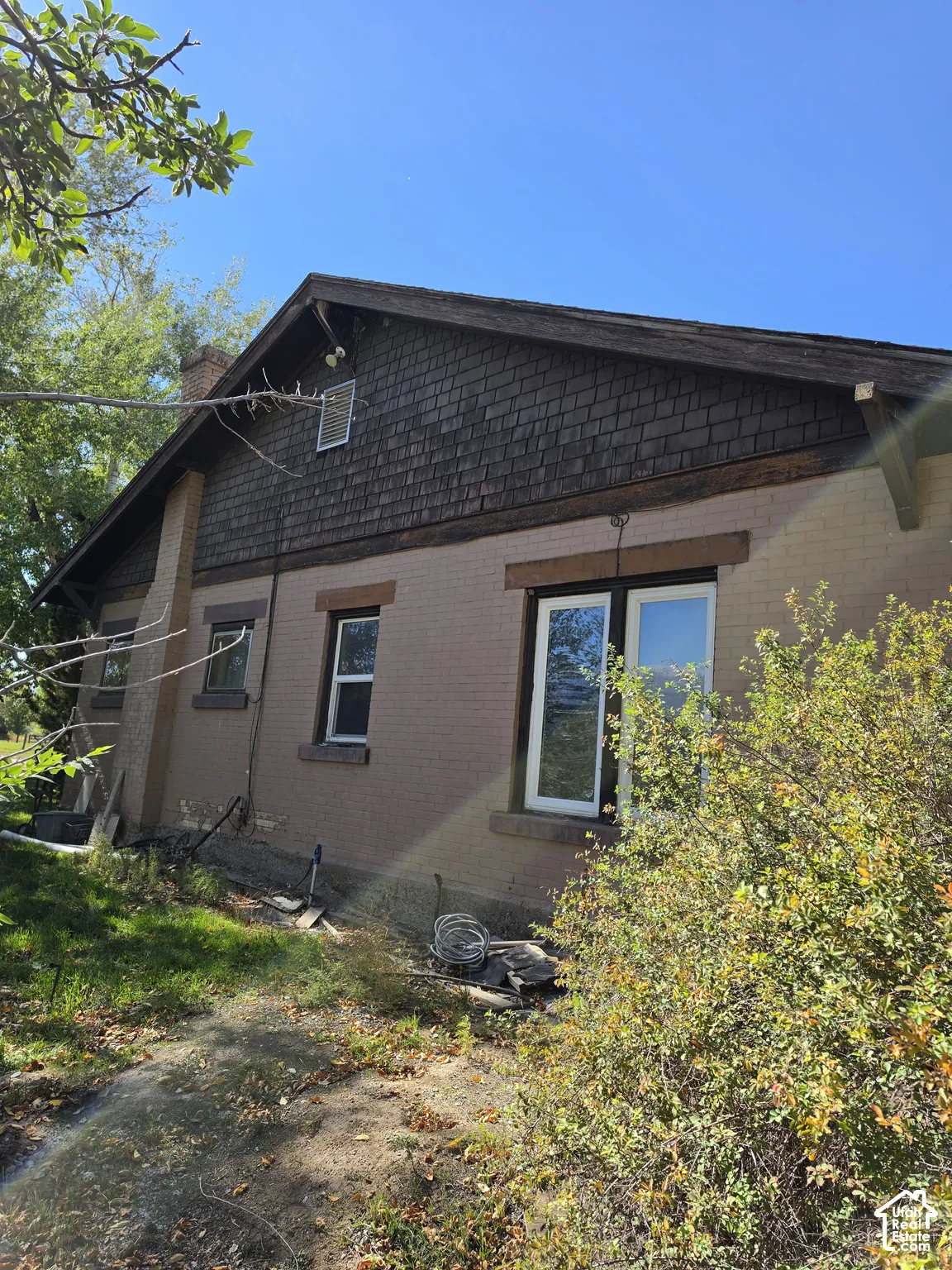 Exterior featuring painted brick construction, wood shingle gable siding, and exposed rafter tails