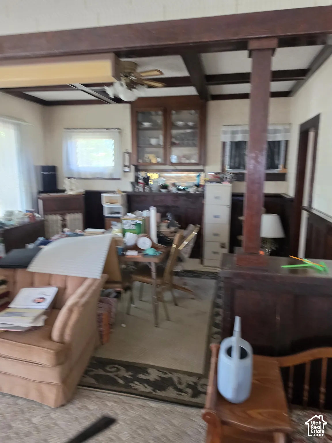 Interior space featuring exposed wood-beam ceiling, built-in glass-front cabinetry, dark wood wainscoting, and a structural square wood column