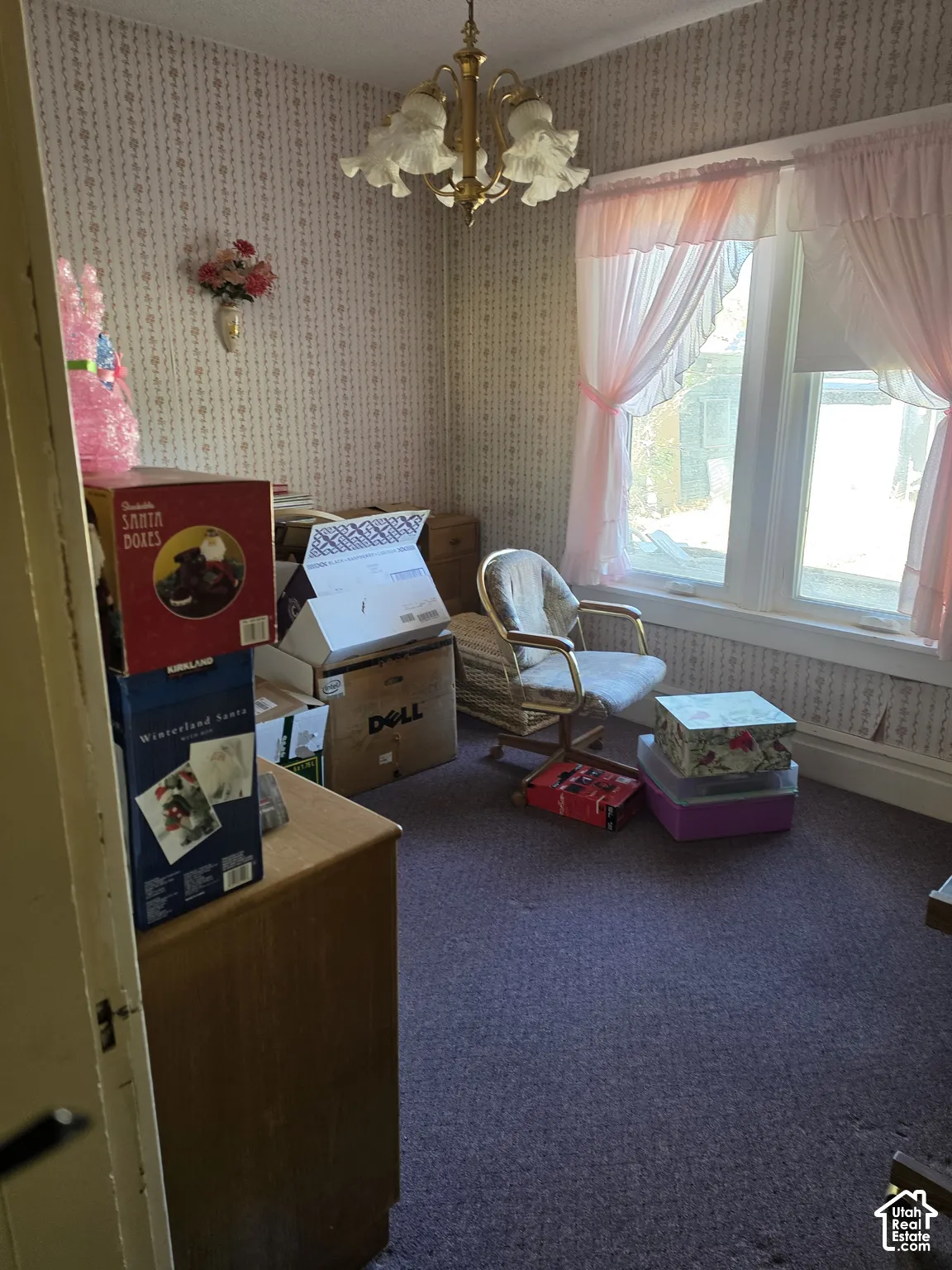 Interior room featuring patterned wallpaper, a multi-light brass chandelier, and a large window
