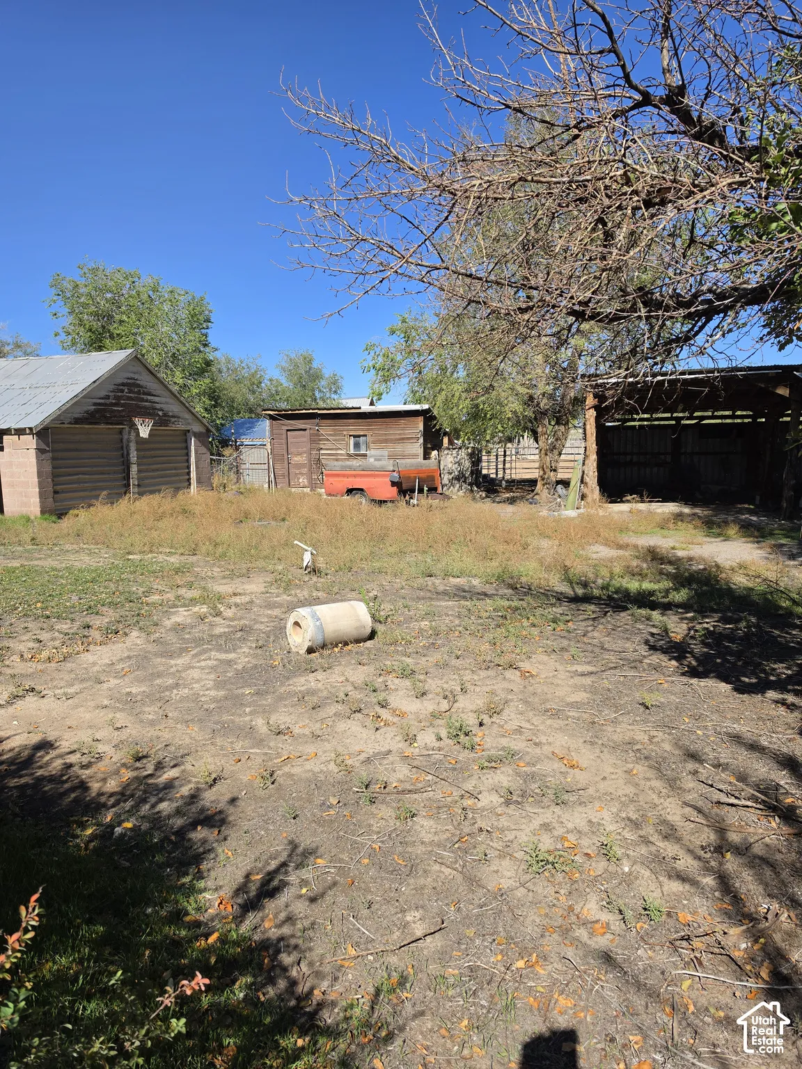 Expansive lot featuring a detached garage, wood-sided outbuilding, and open-sided storage structure