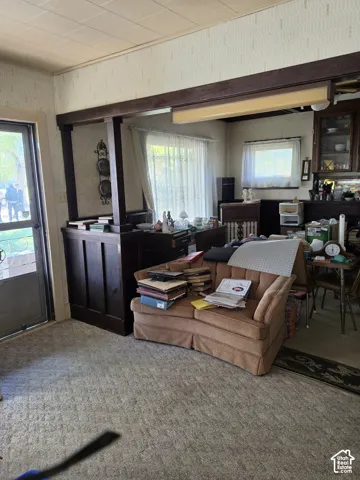Interior featuring dark-stained wood half-wall partition with structural post, built-in glass-front cabinetry, and window with textile valance