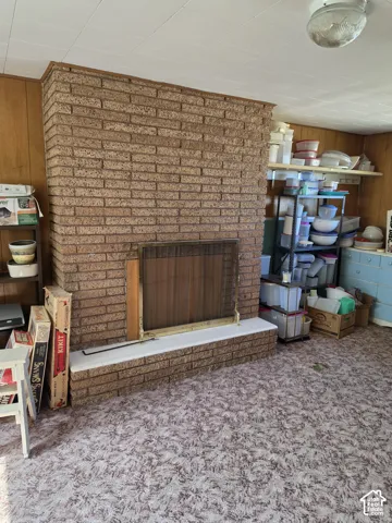 Floor-to-ceiling textured masonry fireplace featuring a hearth and integrated brass fire screen
