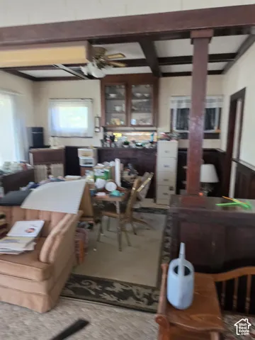 Interior space featuring exposed wood-beam ceiling, built-in glass-front cabinetry, dark wood wainscoting, and a structural square wood column