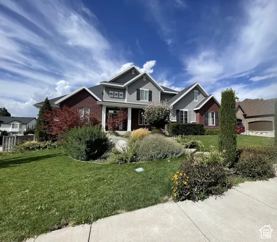 Multi-gabled exterior featuring brick and horizontal siding, covered entryway with columns, and manicured landscaping