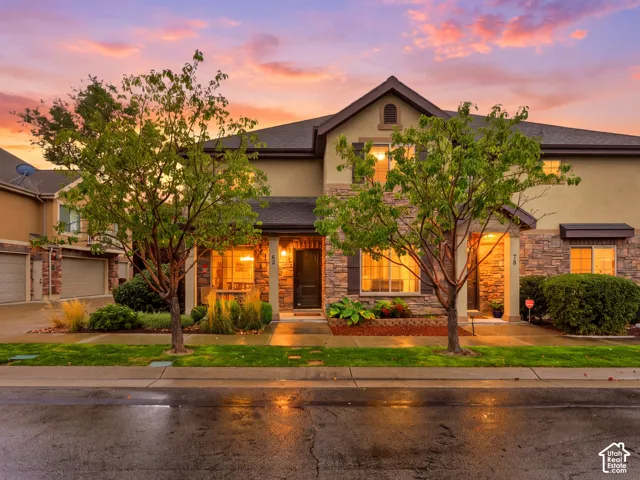 Multi-family exterior featuring stone veneer siding, dual-pitch rooflines, covered entryways, attached garages, and professional landscaping